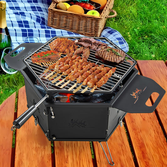The outdoor grill placed on a wooden table with a picnic basket and blanket nearby