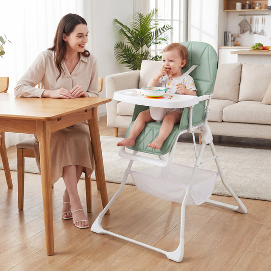 A woman and a baby sit at a table with the green high chair