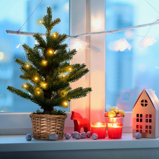 The mini Christmas tree on a windowsill with candles and a house-shaped lantern
