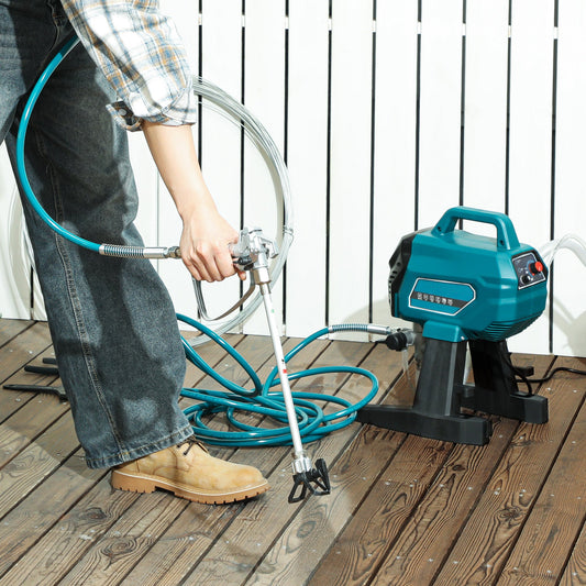 The electric paint sprayer being used by a person to coat wooden decking outdoors