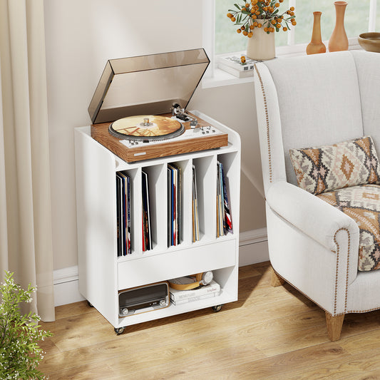 The white end table with a record player on top and vinyl records in the compartments, next to a chair