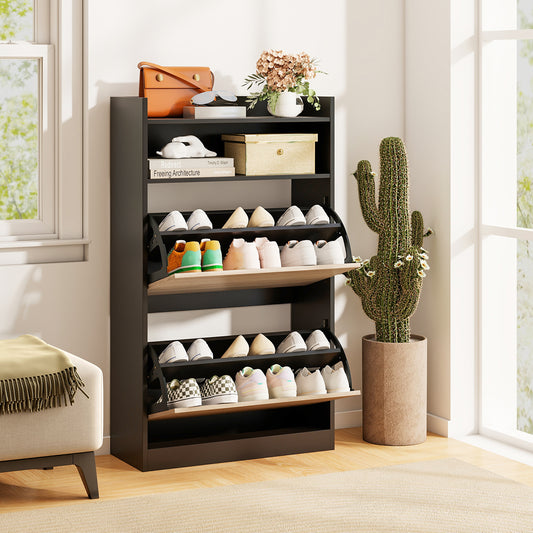 Black shoe storage cabinet with two flip drawers and open storage, shown in a room setting with a plant and sofa
