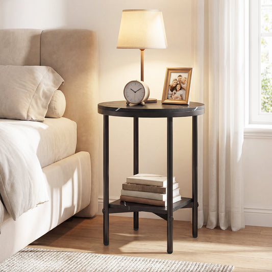 The round end table with faux marble top is placed next to a bed with a lamp and books