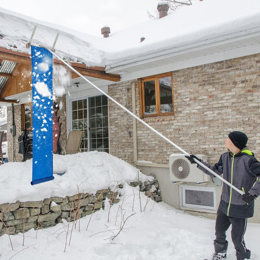 A person using the snow roof rake to clear snow from a roof