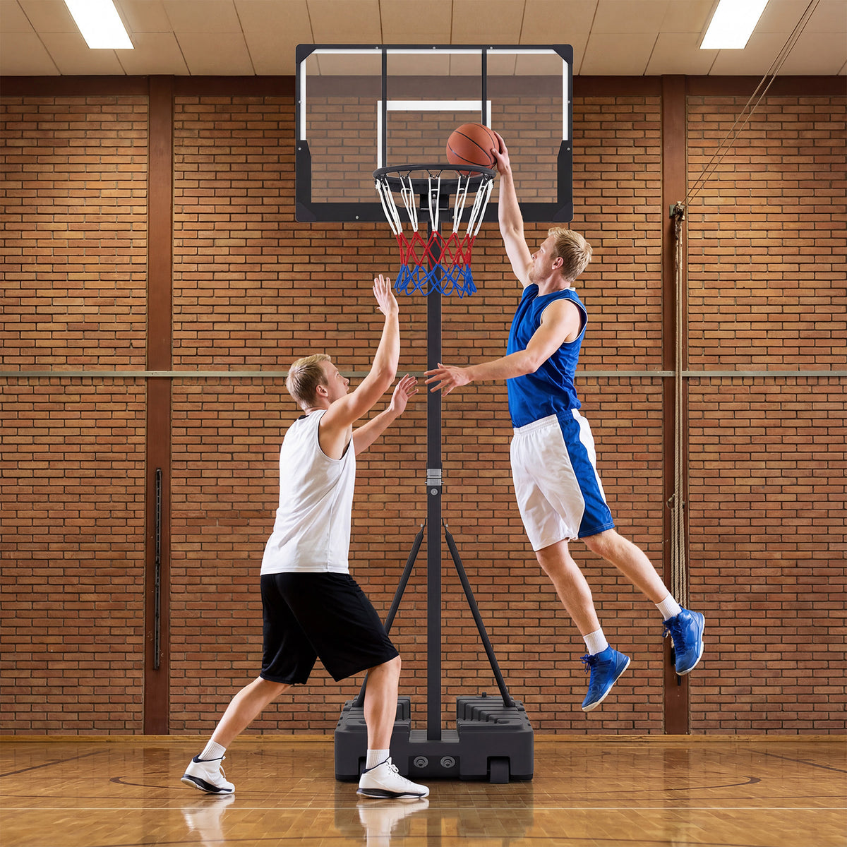 The basketball hoop placed inside a sports hall with two men playing basketball
