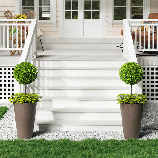 Two tall round planters with topiary balls on a porch