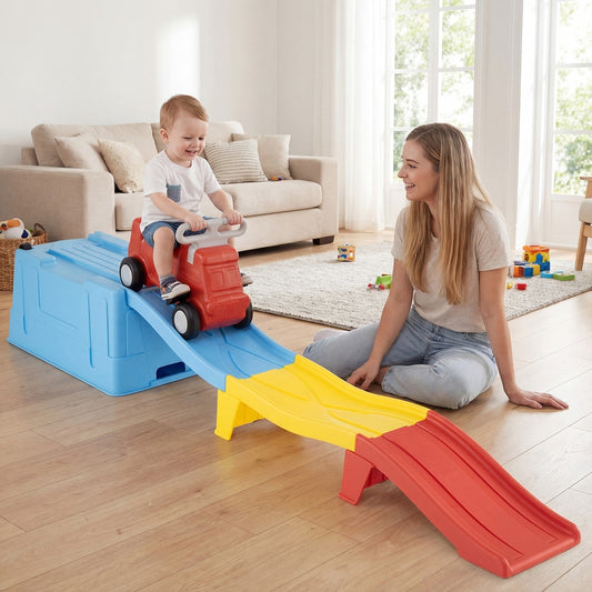A toddler rides the red car down the blue, yellow and red track while a woman watches
