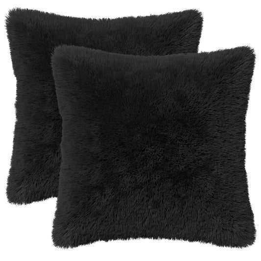 Two black fluffy throw pillows on a plain background