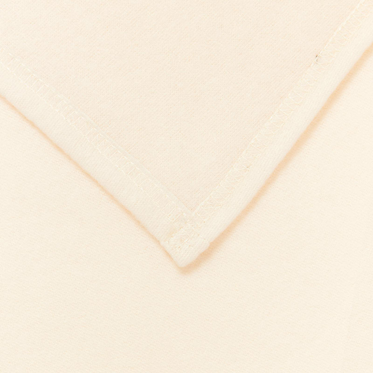 Close up of the corner of a cream fleece blanket showing stitching