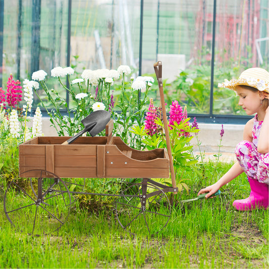 The brown wood wagon planter with wheels, a shovel and a girl in a straw hat in a garden