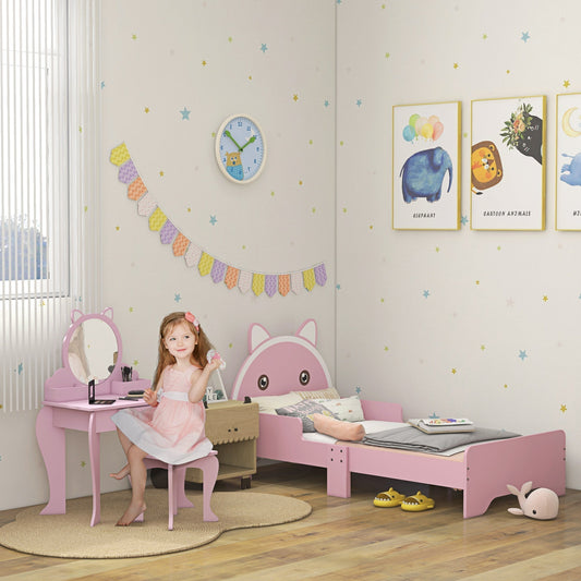 A young girl sits at the pink cat-design dressing table in a child's bedroom, with the matching bed nearby