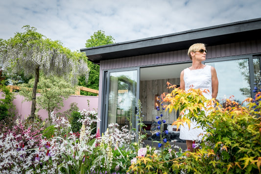 Woman in white dress standing in a lush garden.