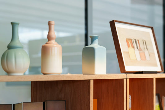 Decorative vases and framed art on a light wooden shelf