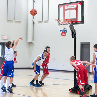 Several children play basketball with the adjustable hoop indoors on a wooden floor