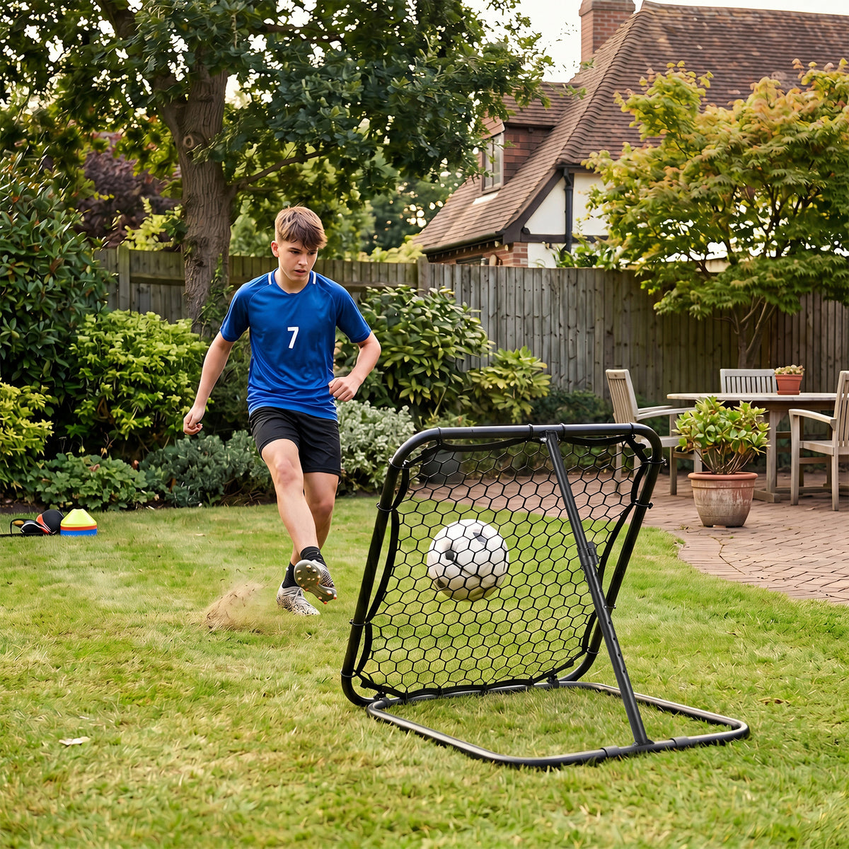Teenager practising football with the rebounder in a garden setting
