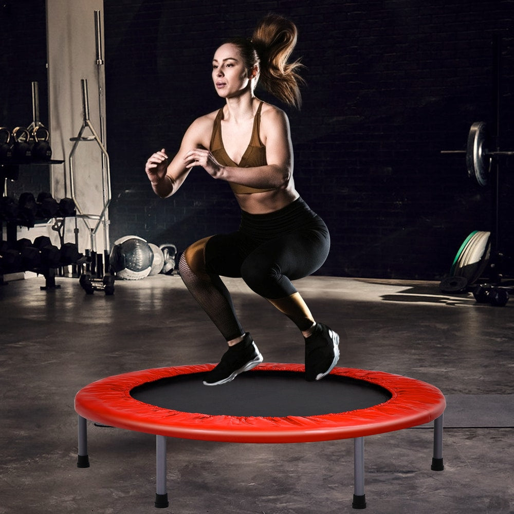 A woman exercising on the red trampoline in a gym setting