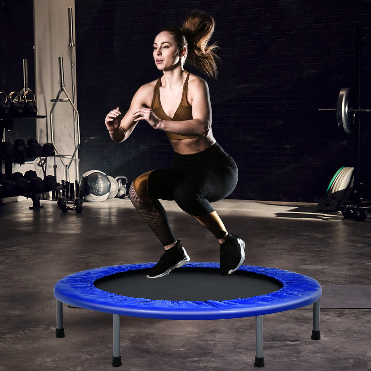 The blue trampoline being used by a woman in a gym setting