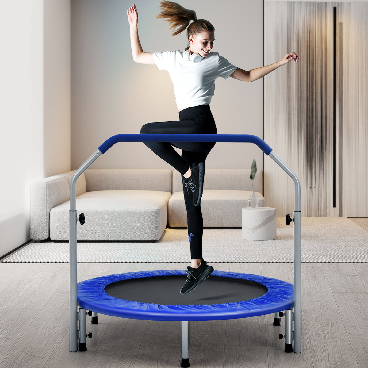 The blue trampoline being used by a woman indoors in a living room setting