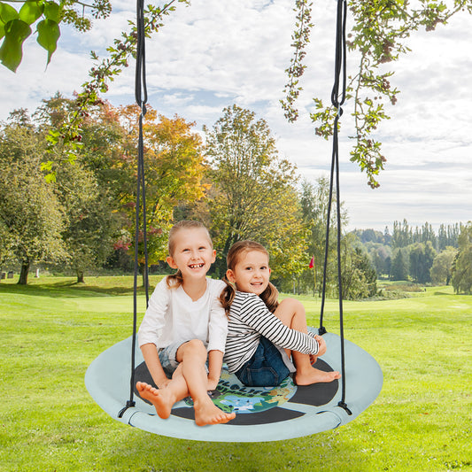 Two young girls smiling while sitting on the round tree swing in a garden setting