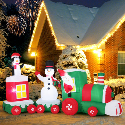 The Christmas inflatables train with snowman and penguin lit up at night outside a house