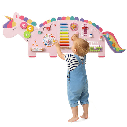 A toddler reaching for the unicorn activity wall busy board panels