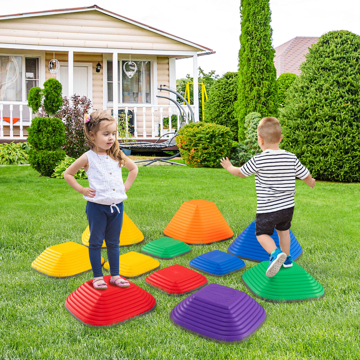 Two children play on colourful stepping stones arranged on a lawn in front of a house