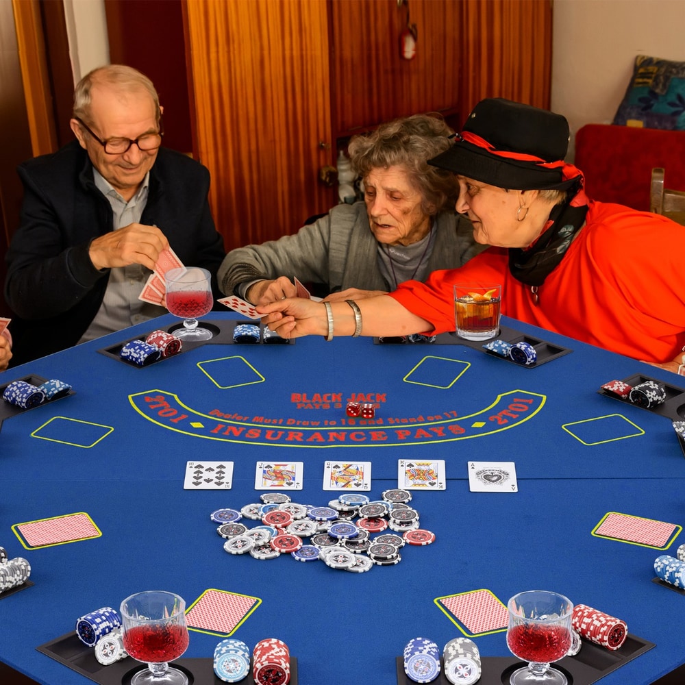 Three older people playing cards at the blue poker table top