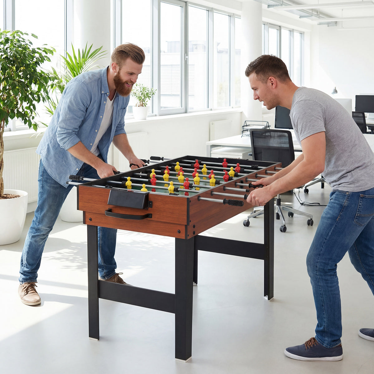 Two men playing foosball on the multi games table in an office setting