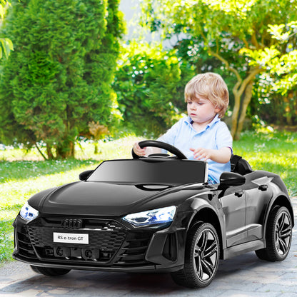 A young boy drives the black electric ride on car in a garden setting