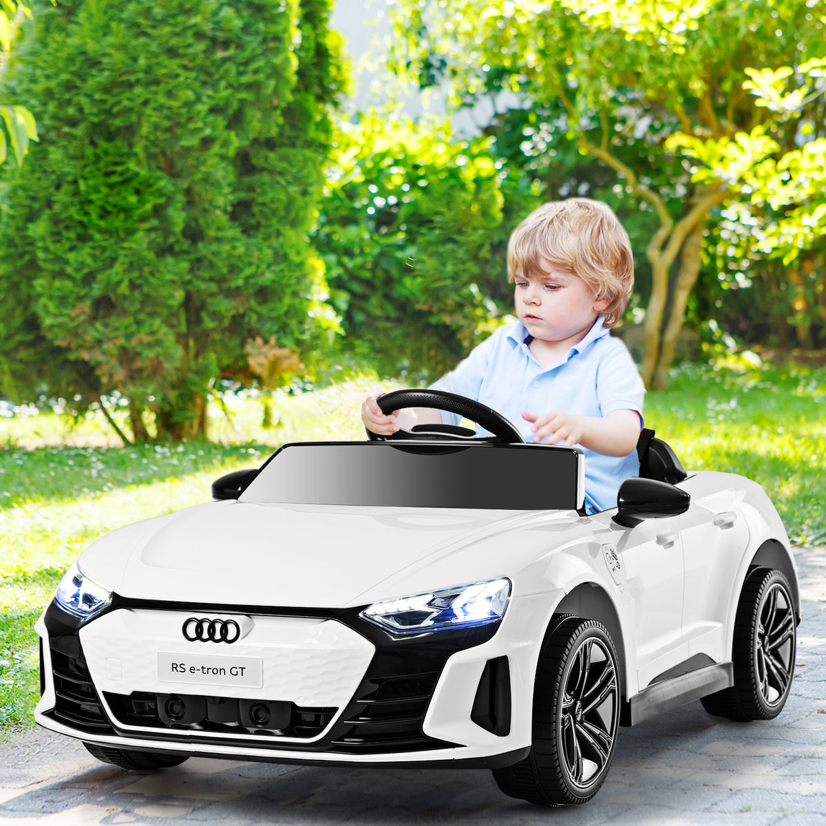 A young boy drives the white kids electric car in a garden setting