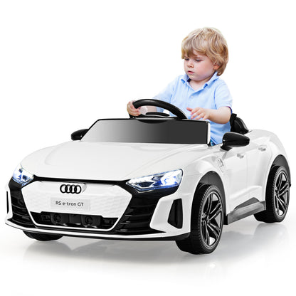 A young boy sits in the white kids electric car, ready to drive