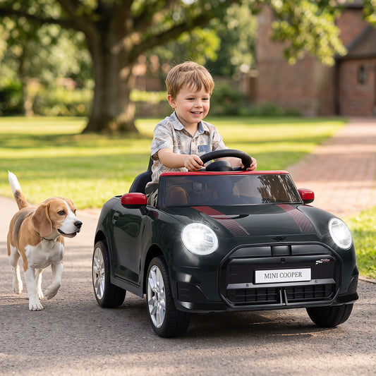 A happy child rides the black electric car with a dog running alongside