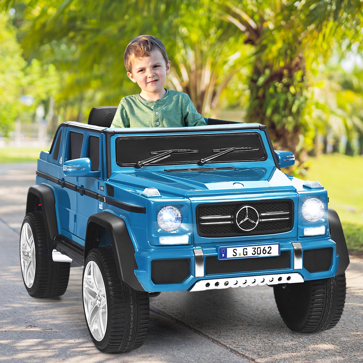 The kids electric car being driven by a young boy on a paved path in a sunny park