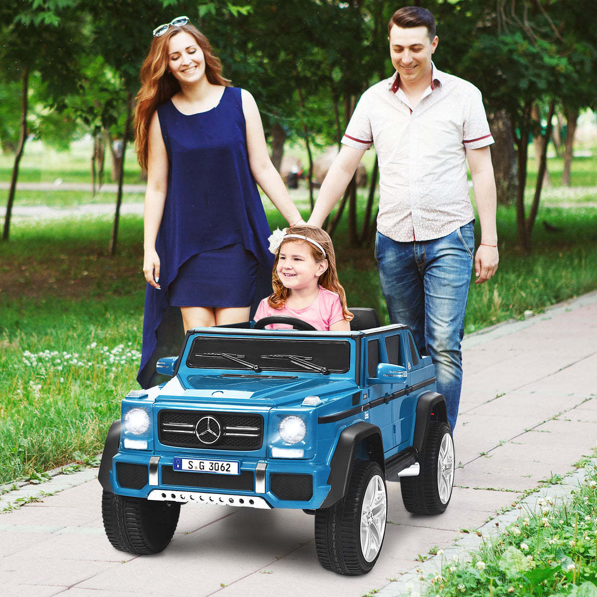 The kids electric car with a young girl sitting inside while parents walk alongside her