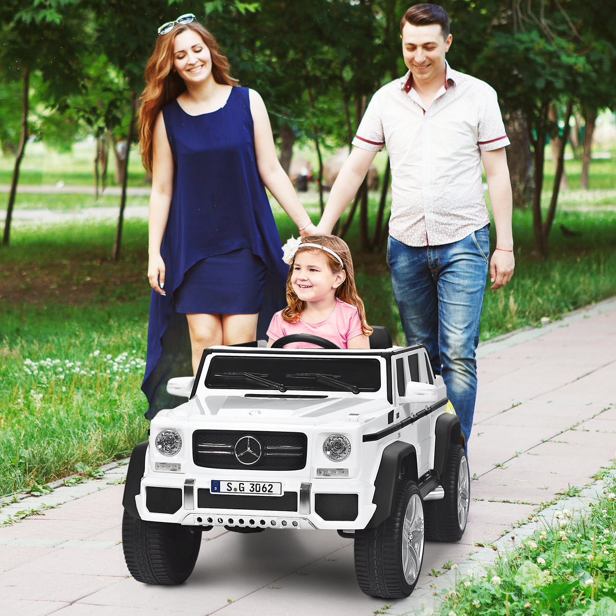 The kids electric car with a young girl inside being guided by parents