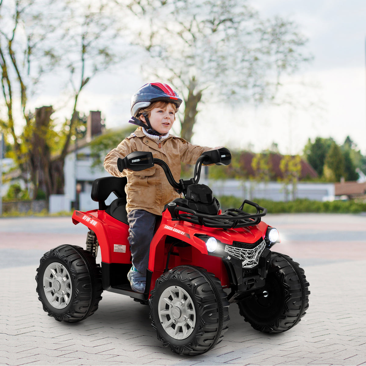 A young boy wearing a helmet riding the kids electric car on a paved driveway