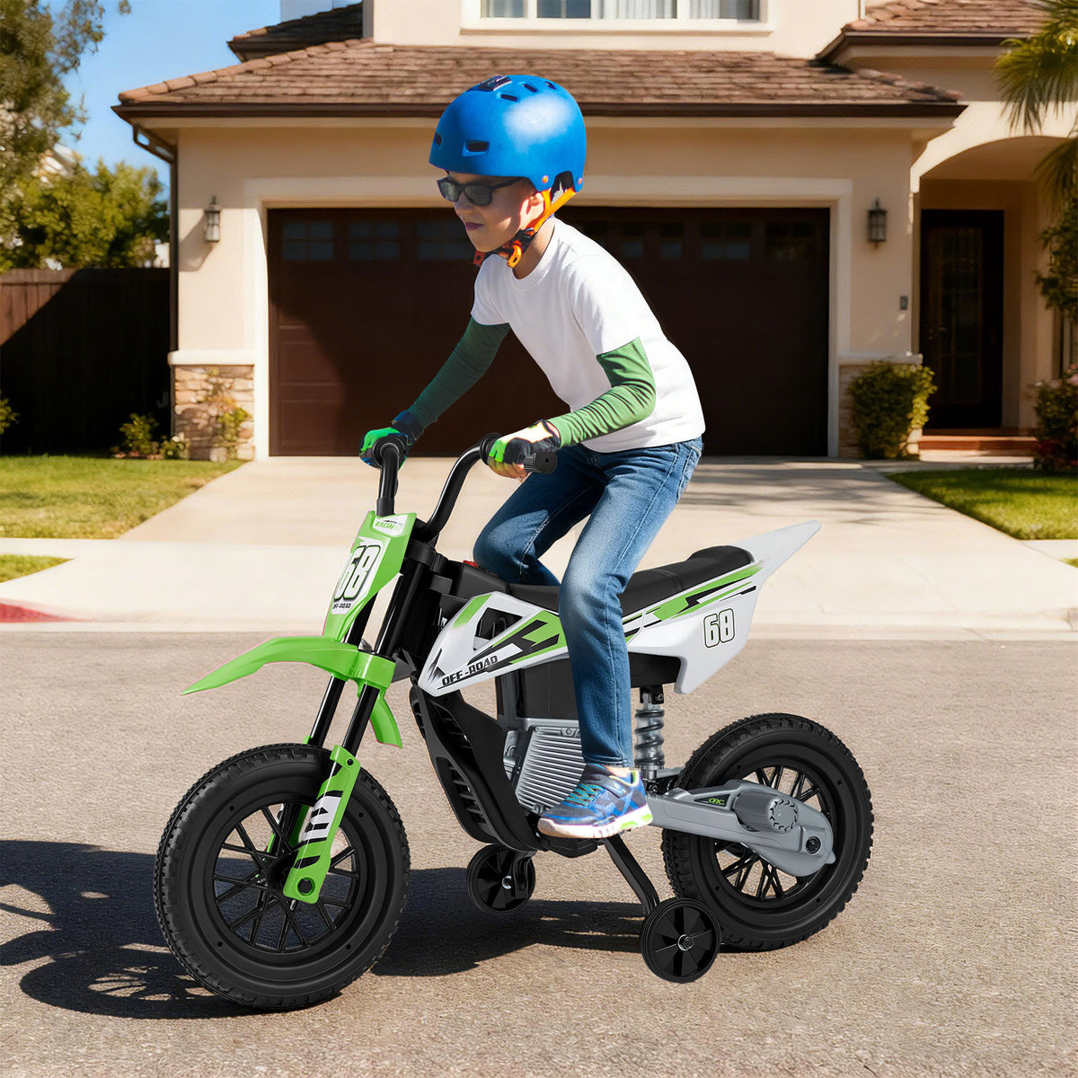 The kids electric motorbike being ridden by a boy wearing a blue helmet on a residential driveway
