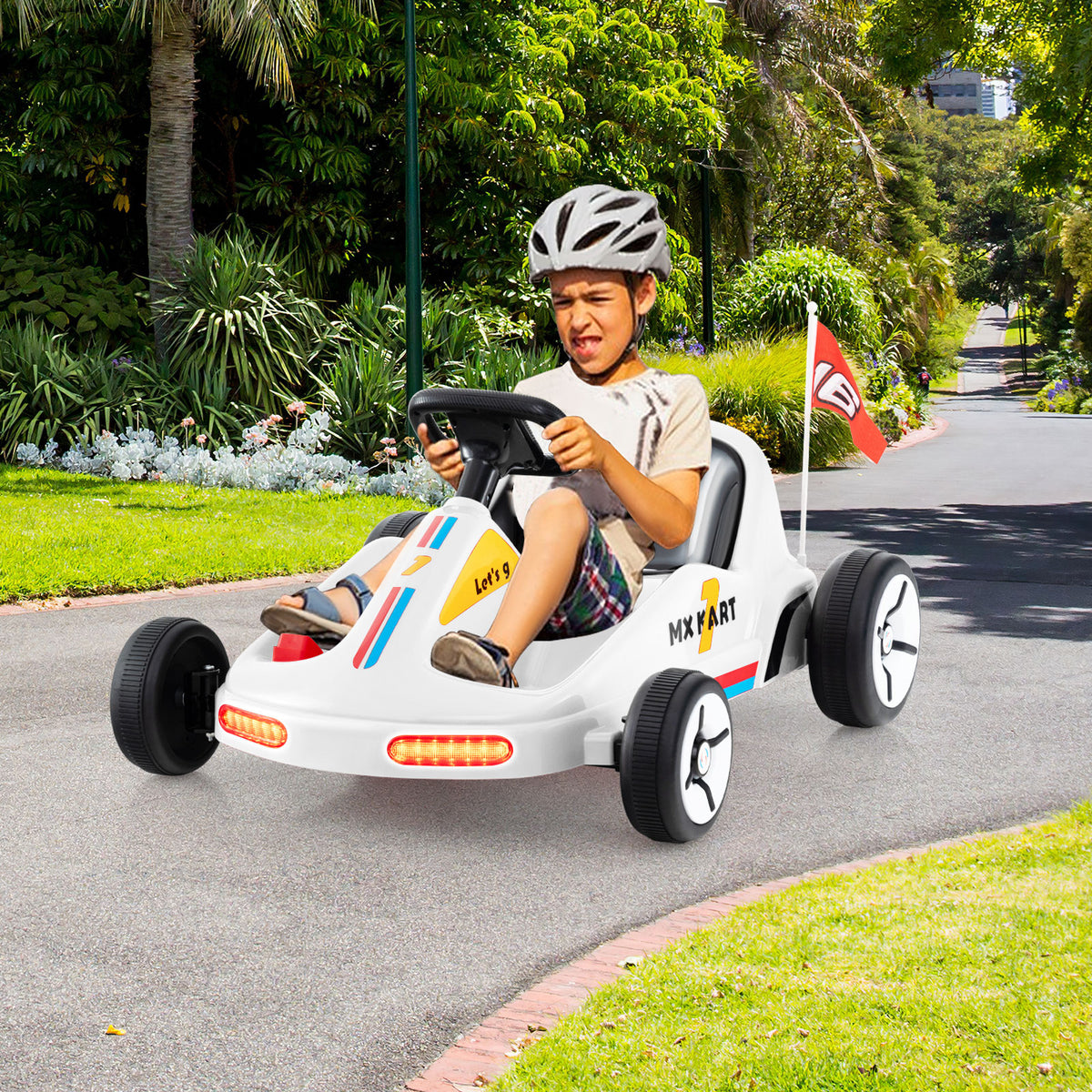 Boy driving a white electric go kart on a path with trees