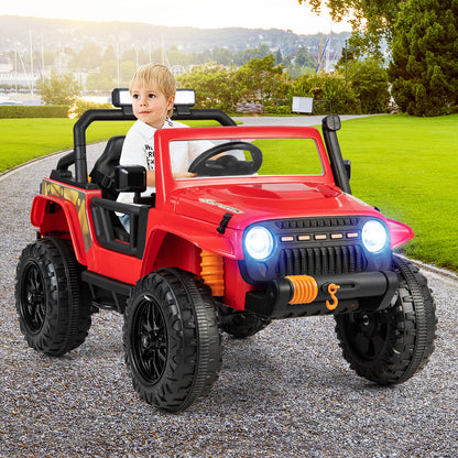 A young boy sits in the red kids electric car outdoors