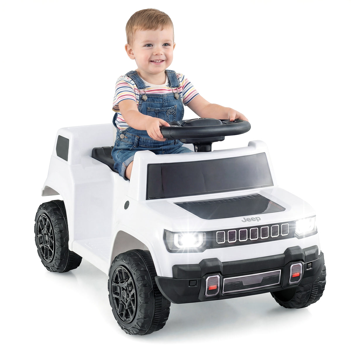 Smiling young boy in denim overalls sits in the white electric jeep car