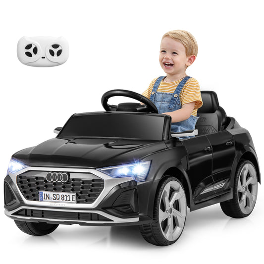 A happy toddler sits in the black kids electric car, with a remote control shown above