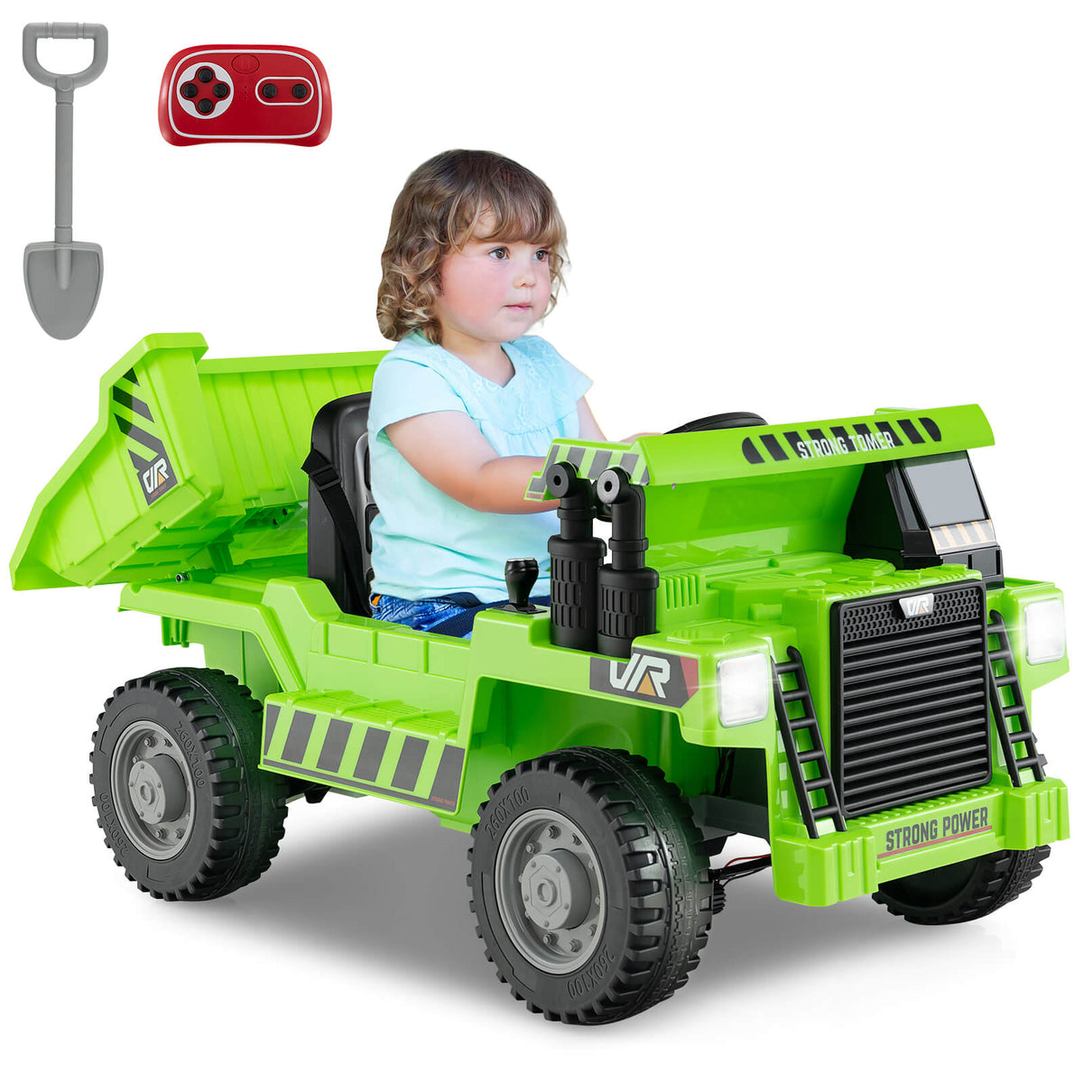 A young child driving the green kids electric dump truck with a remote control and shovel accessory