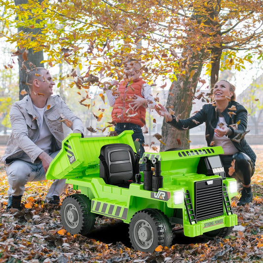 A green kids electric dump truck with a family playing around it outdoors