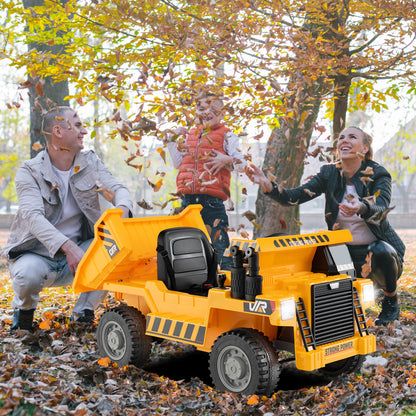 A yellow electric dump truck with a child and parents playing in an autumn park