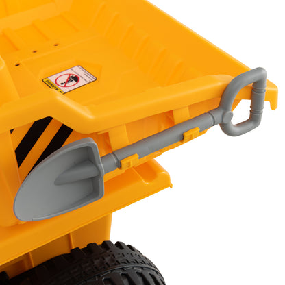 Close-up of a grey plastic shovel attached to the side of a yellow electric dump truck