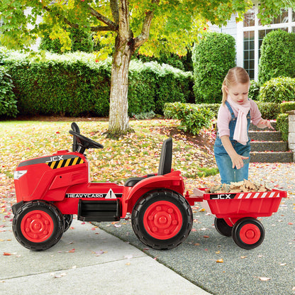 A young girl stands next to the red ride on tractor with trailer in a garden