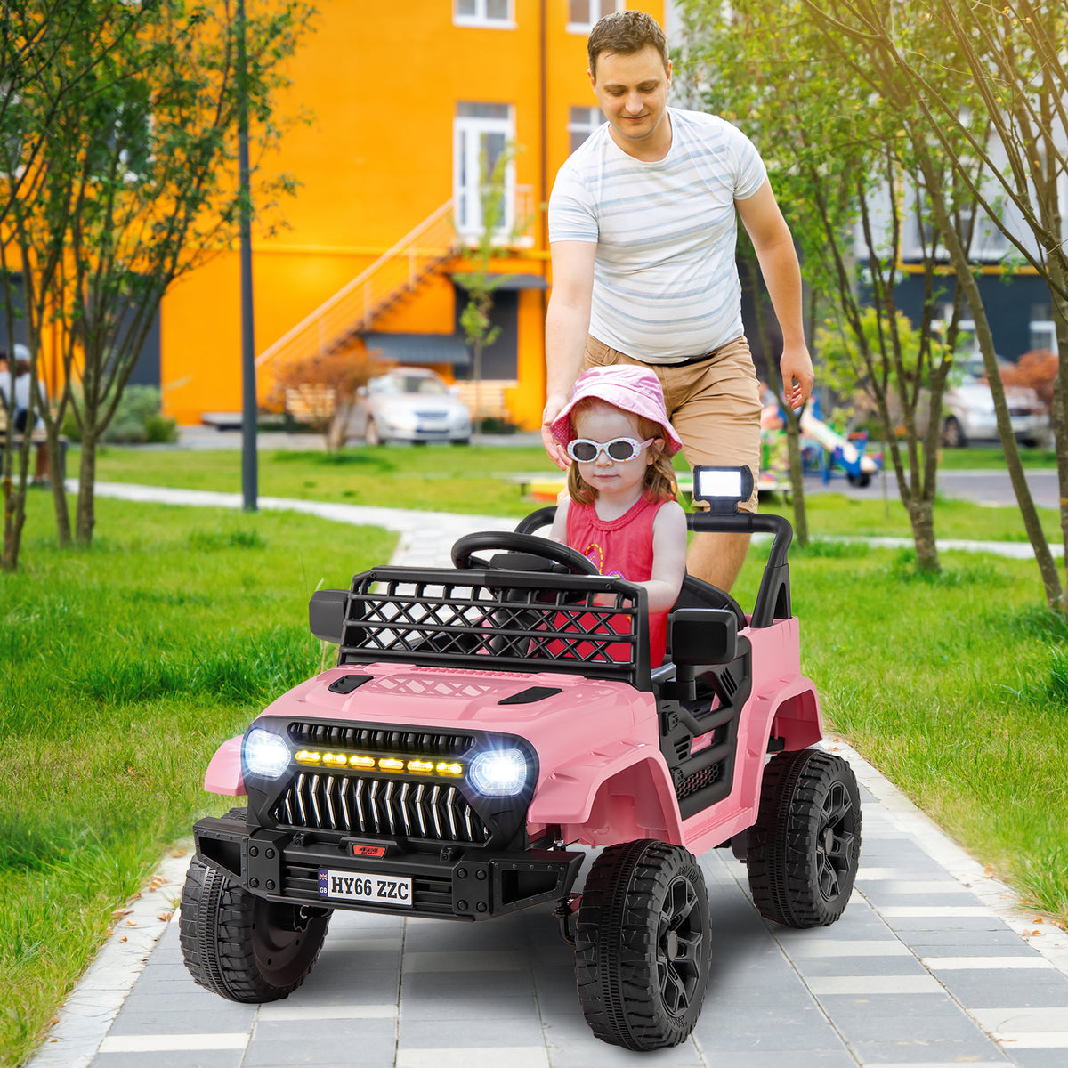 A man helps a child get into the pink kids electric truck outdoors