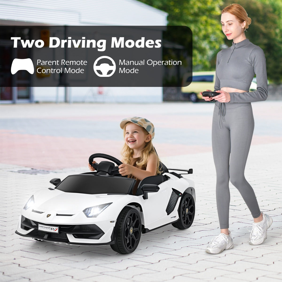 The kids electric car being driven by a child while an adult holds the remote
