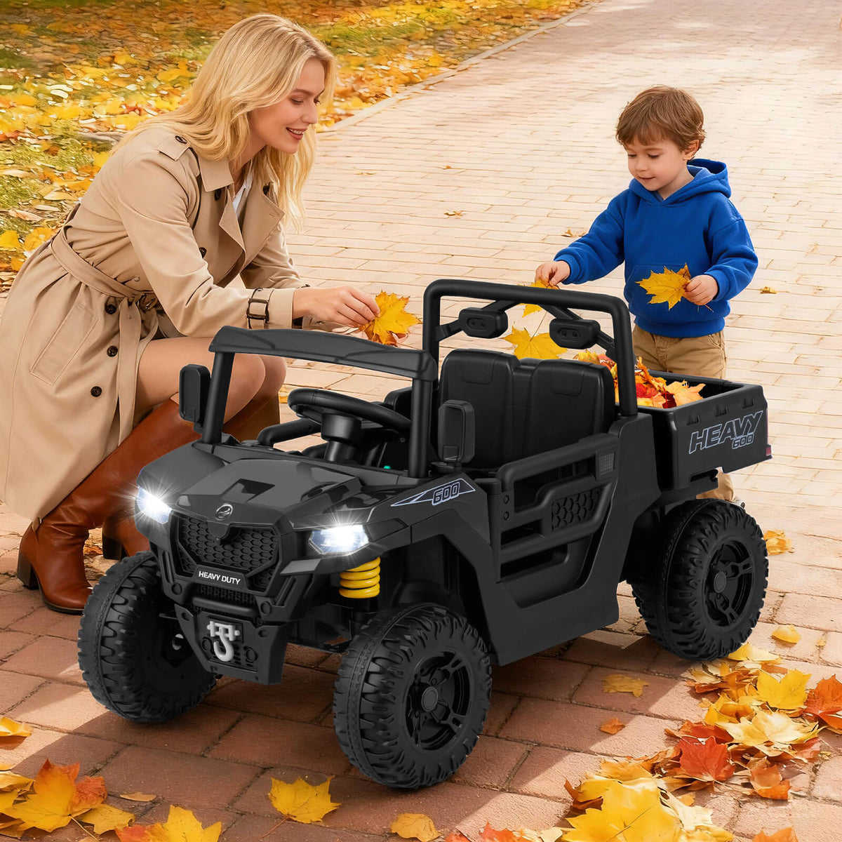 The kids electric car parked on a paved path with a child and adult playing with autumn leaves