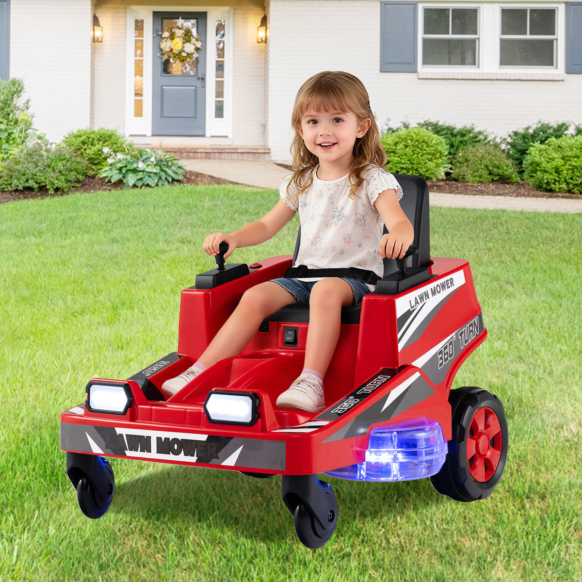 The red ride on lawn mower for kids is being driven by a young girl on a grassy lawn outside a house